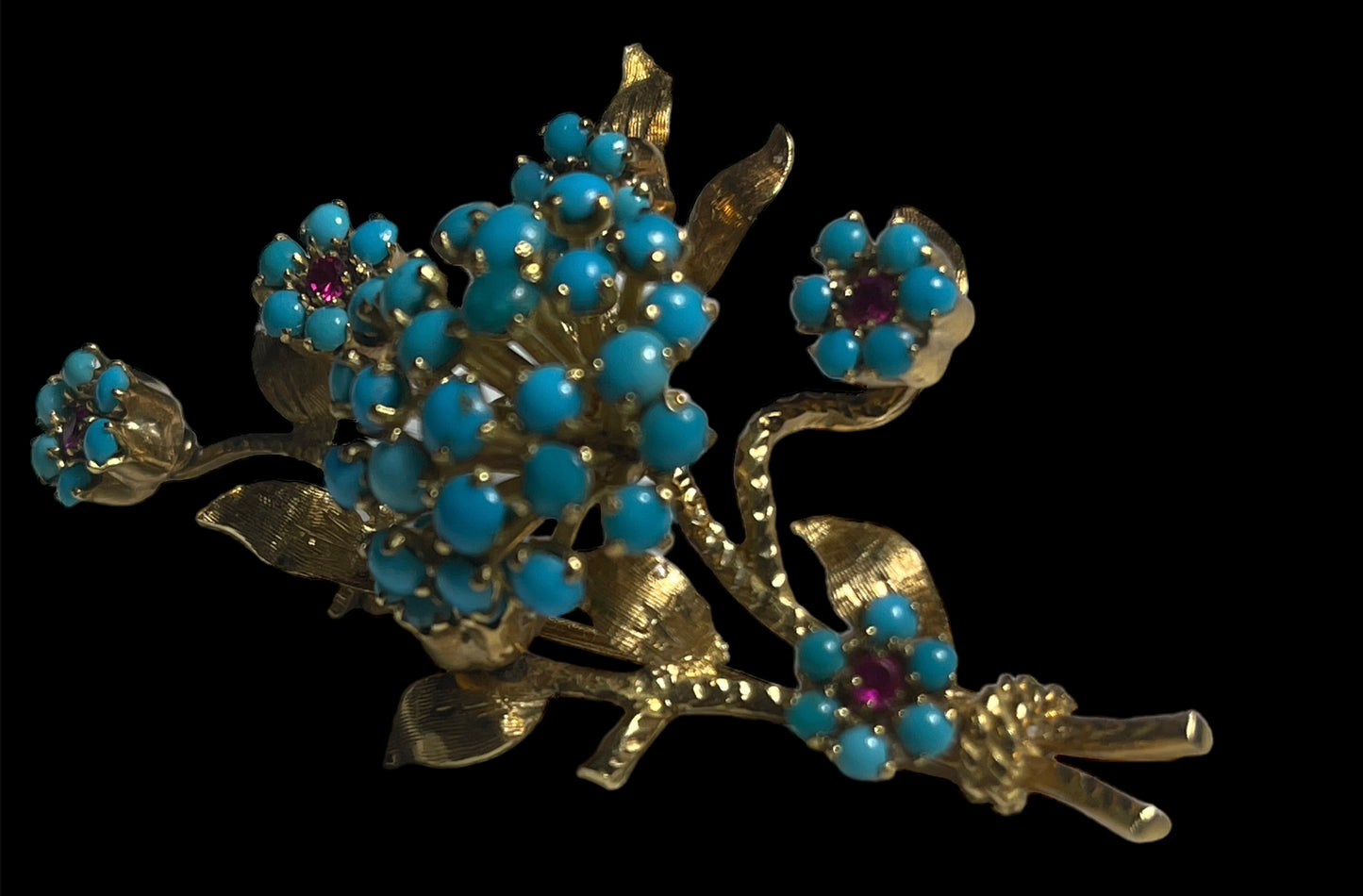 A 14k gold brooch with turquoise and ruby stones
