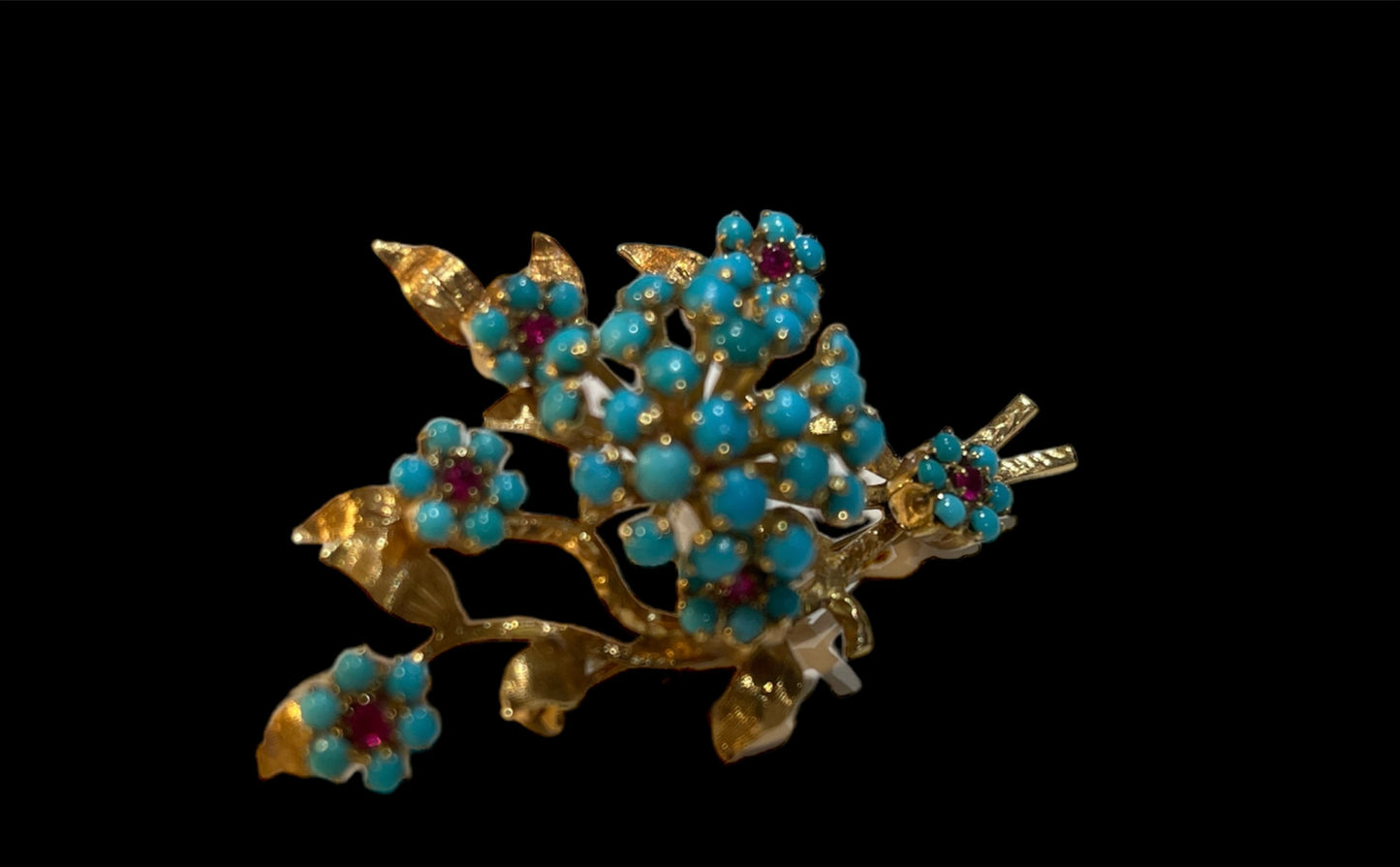A 14k gold brooch with turquoise and ruby stones