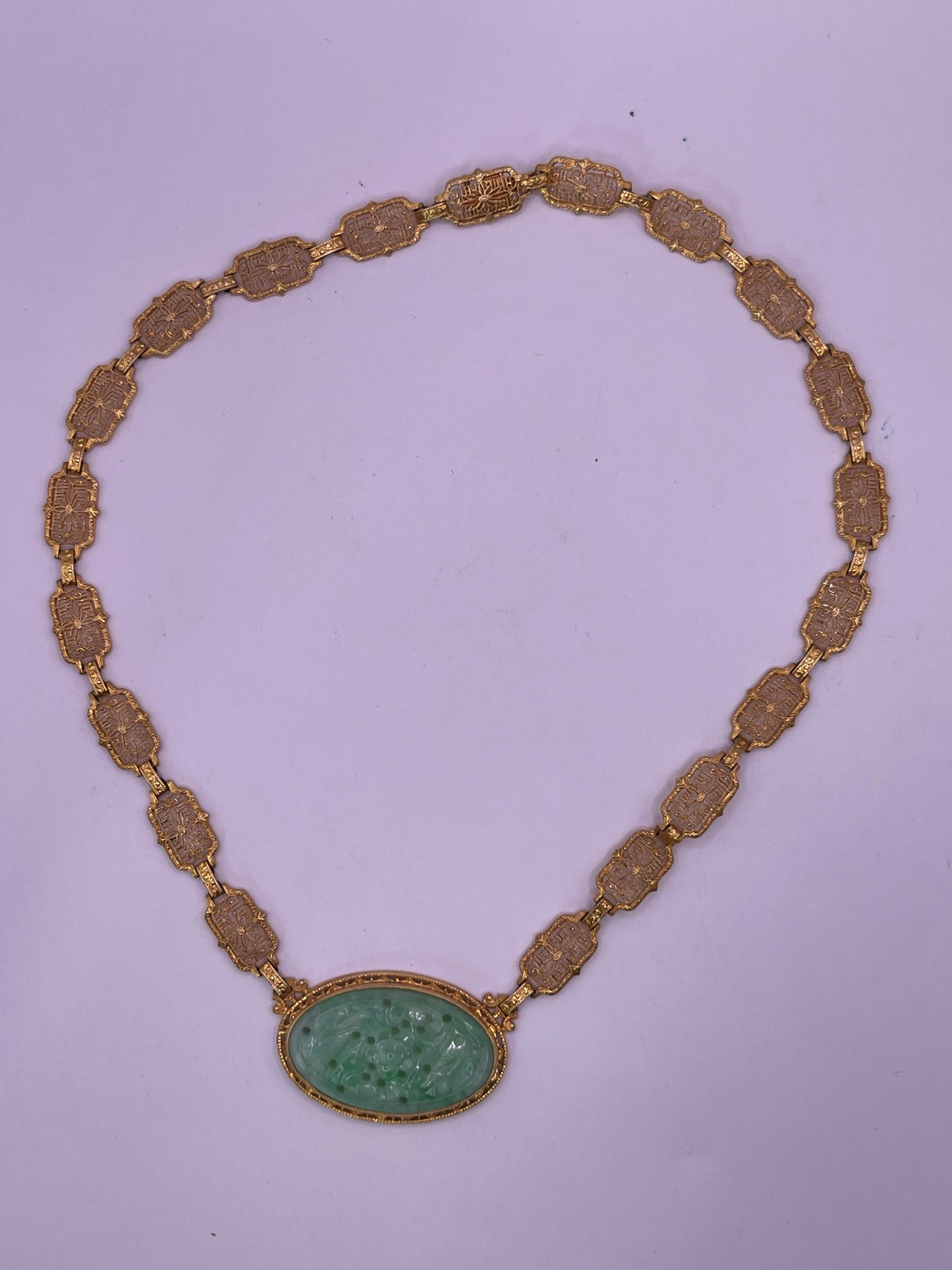 A vintage Art Deco style necklace with a antique apple green jade carved plaque in a 14kt filigree setting