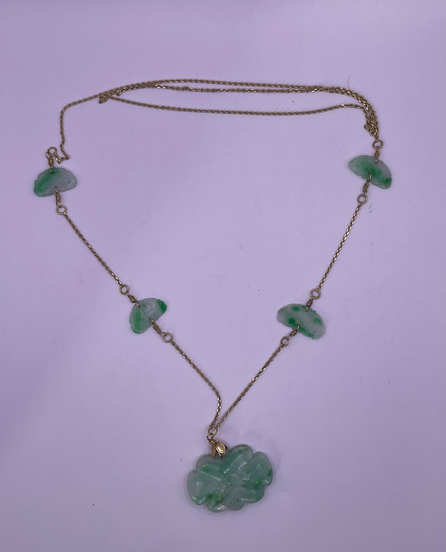 A vintage Art Deco style necklace with an antique apple green jade carved plaque and smaller plaques on 14kt chain
