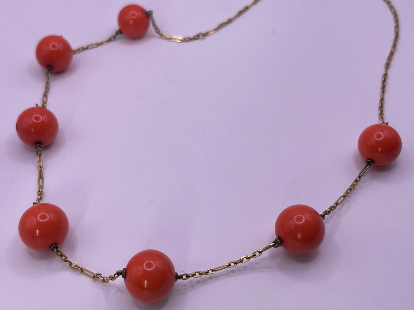 A necklace with coral beads on a 14kt chain