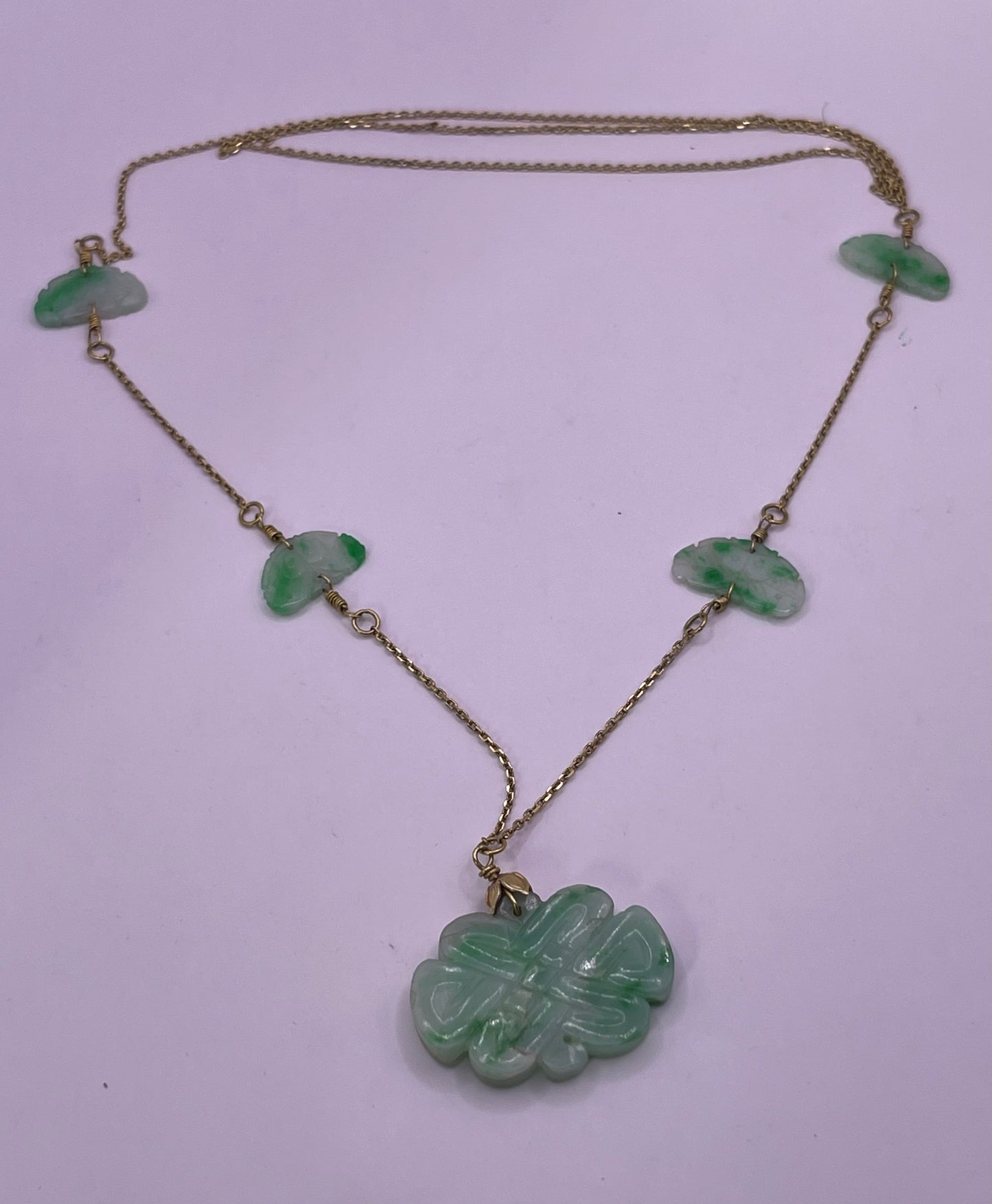 A vintage Art Deco style necklace with an antique apple green jade carved plaque and smaller plaques on 14kt chain