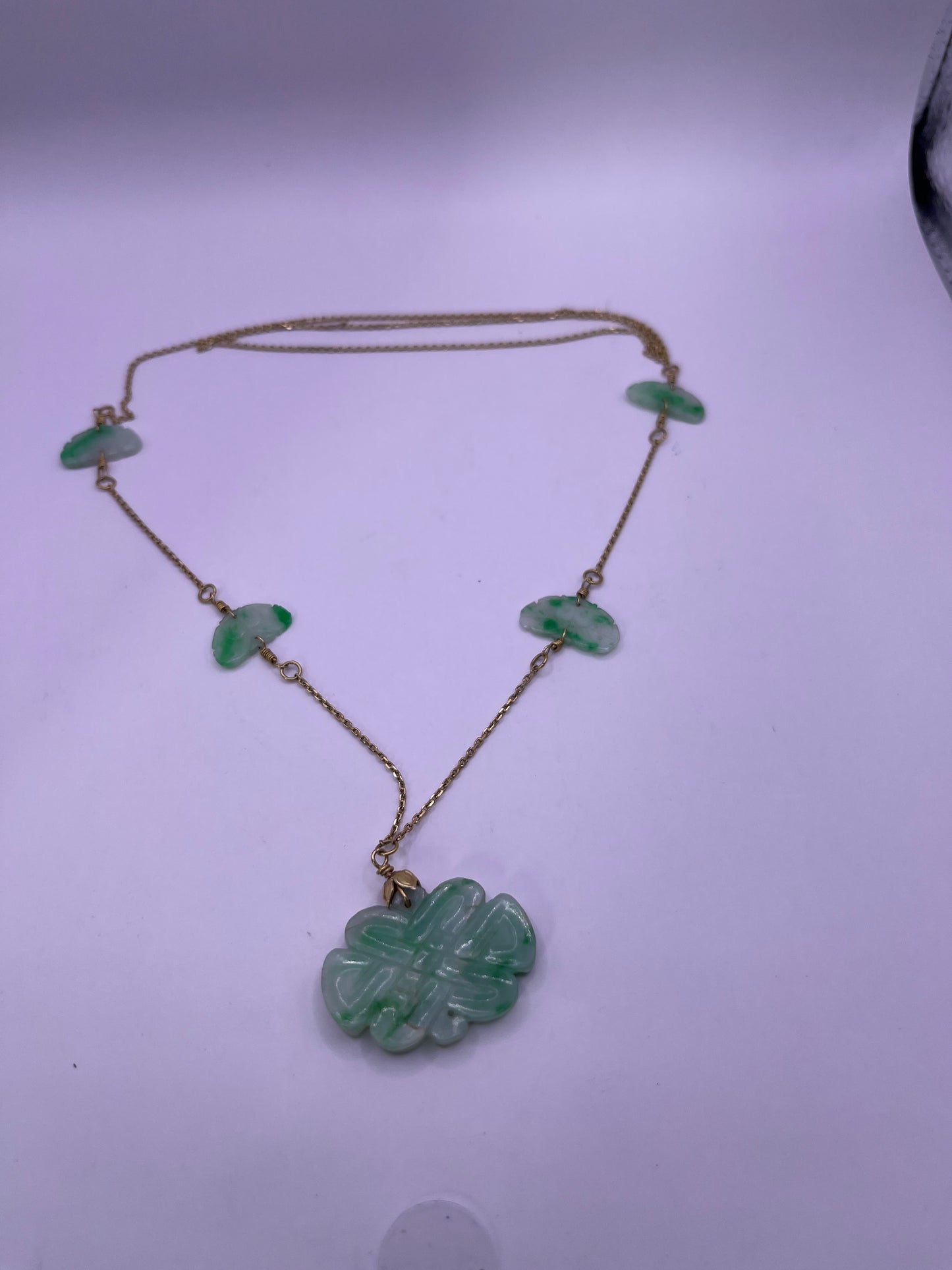 A vintage Art Deco style necklace with an antique apple green jade carved plaque and smaller plaques on 14kt chain