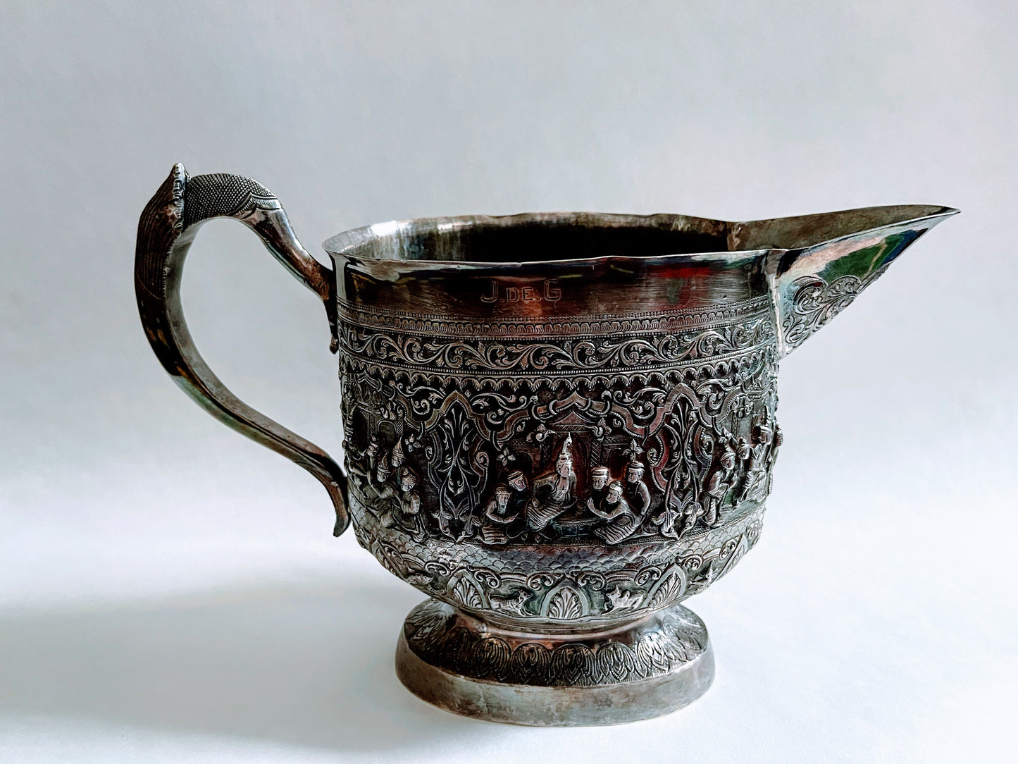 A Burmese antique elaborately carved circular tray and oval shaped jug with a pointed mug.