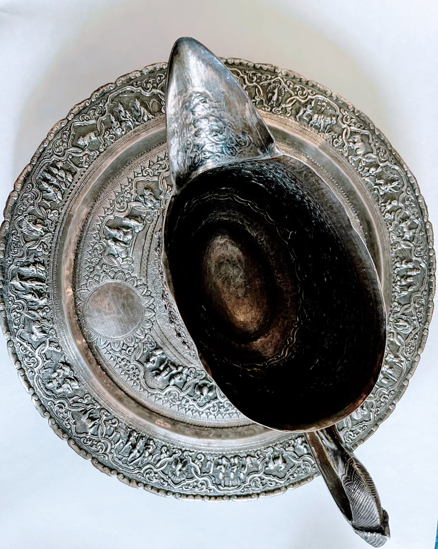 A Burmese antique elaborately carved circular tray and oval shaped jug with a pointed mug.