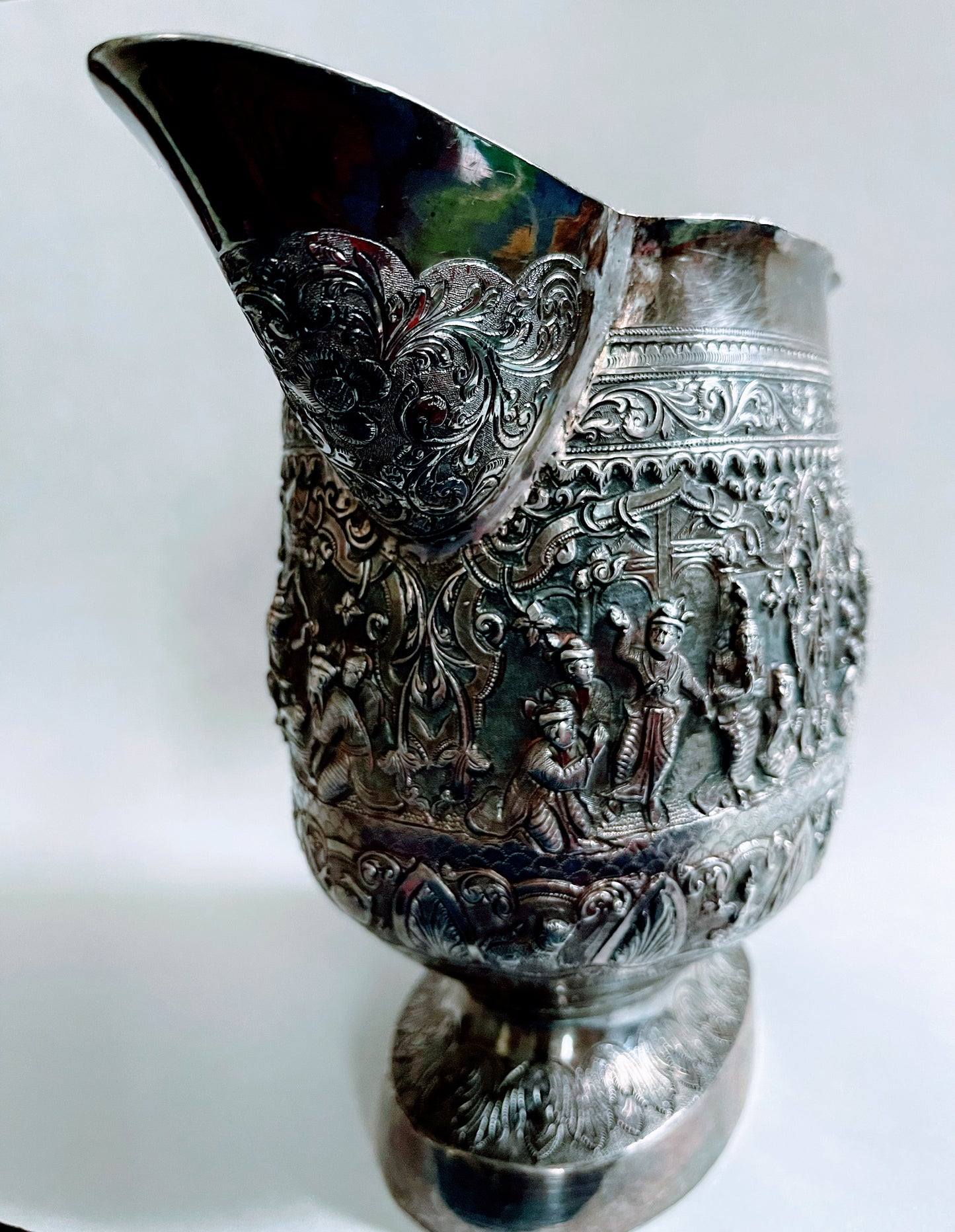 A Burmese antique elaborately carved circular tray and oval shaped jug with a pointed mug.