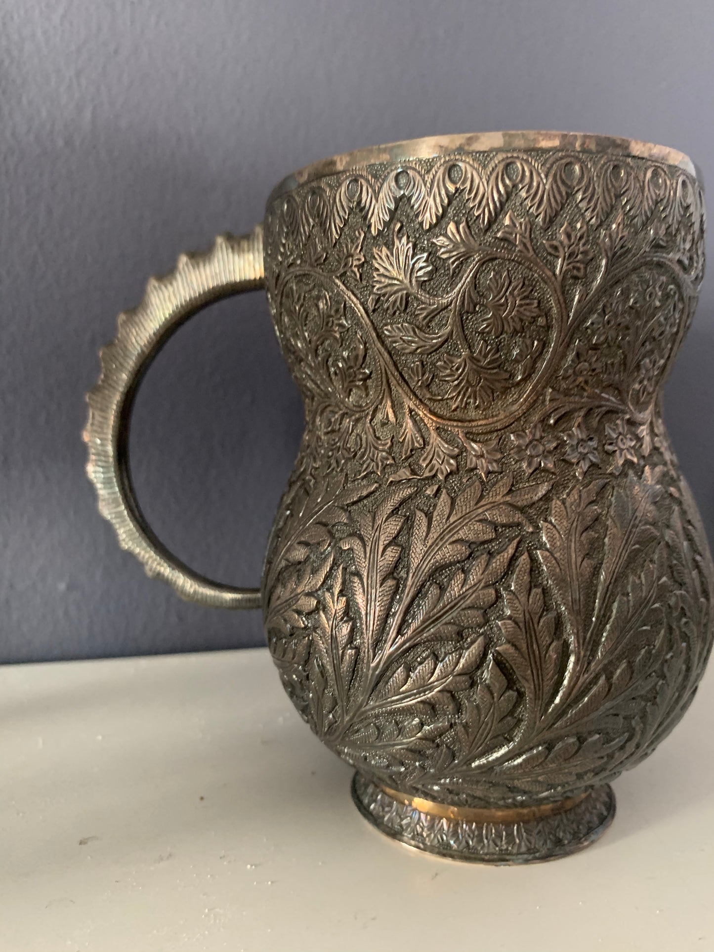 An intricately carved silver mug