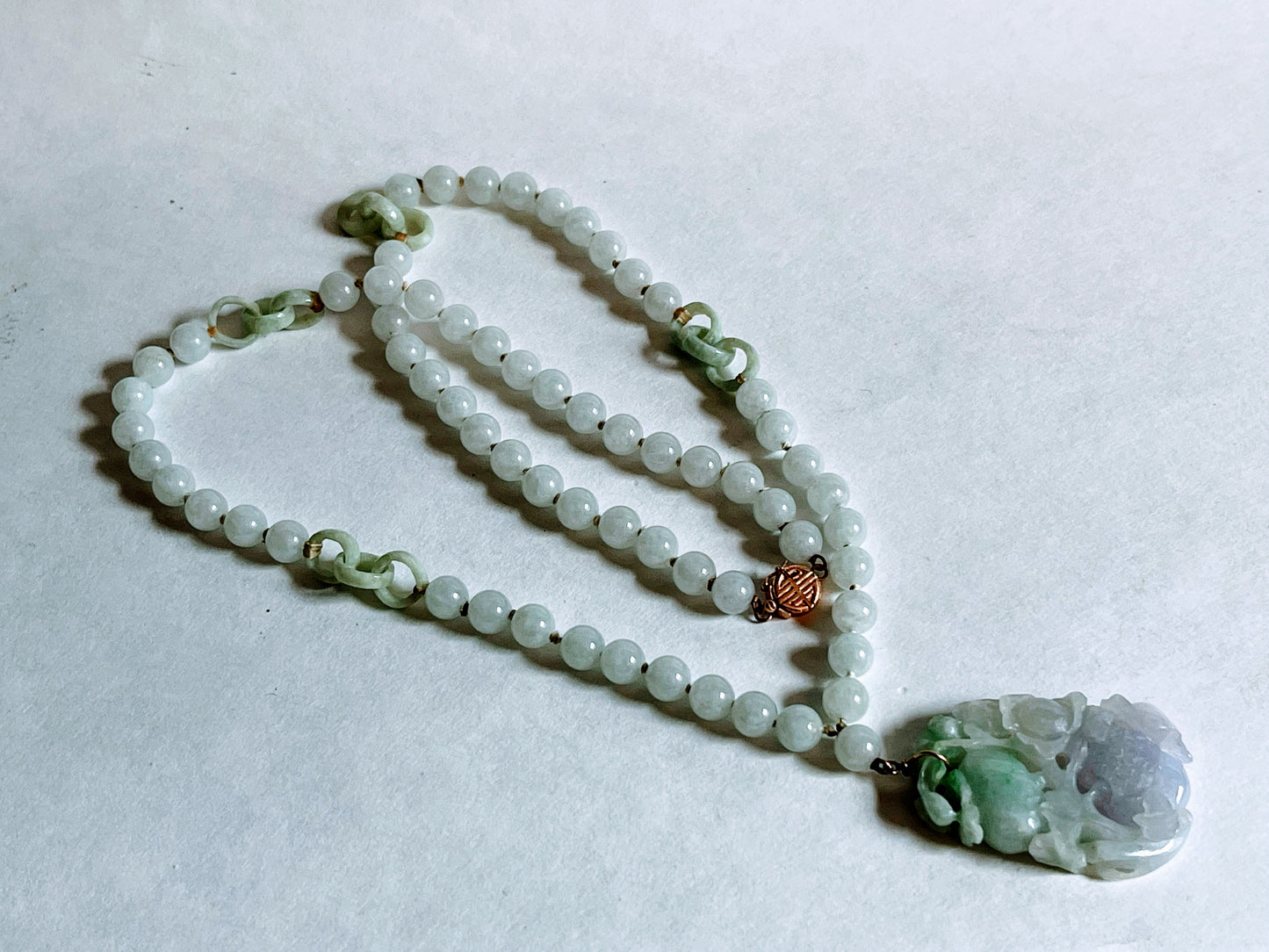 A vintage Art Deco style necklace with a antique apple green jade carved plaque in a 14kt filigree setting
