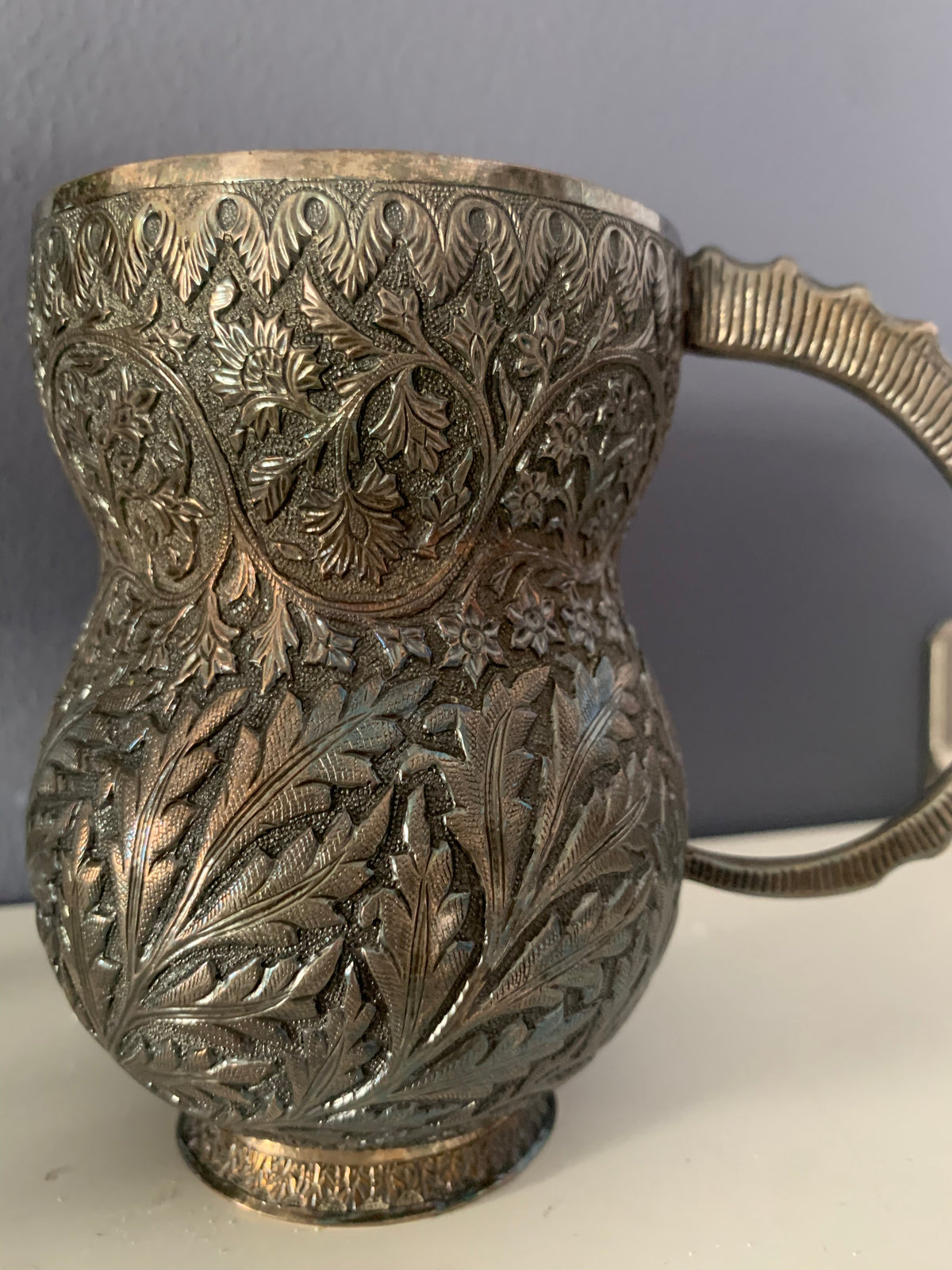 An intricately carved silver mug