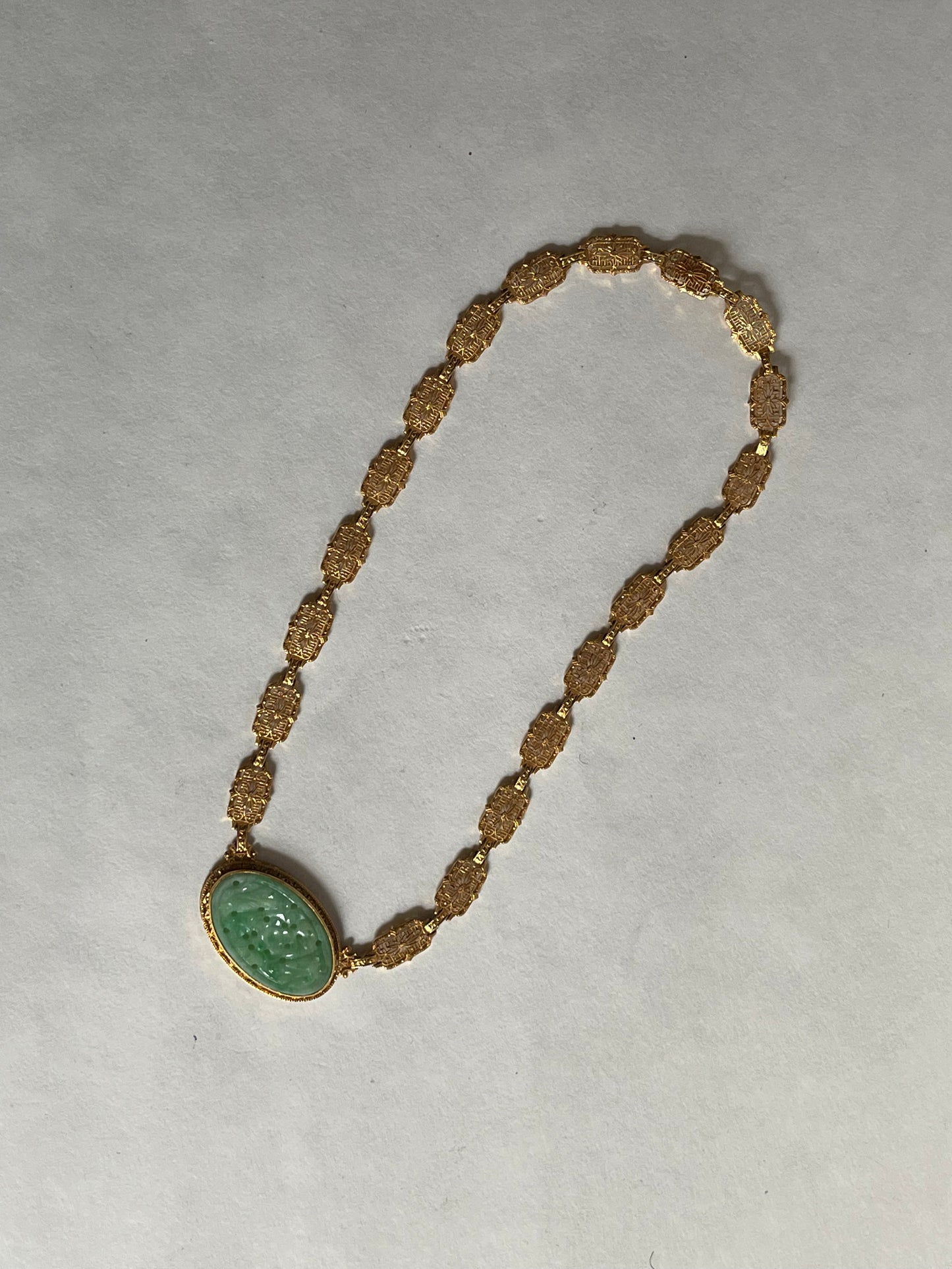 A vintage Art Deco style necklace with a antique apple green jade carved plaque in a 14kt filigree setting