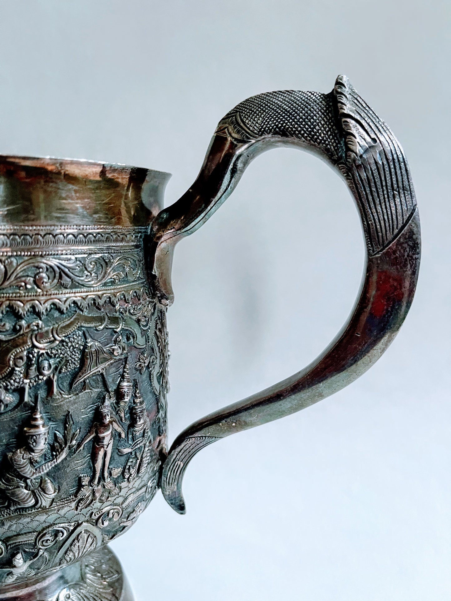 A Burmese antique elaborately carved circular tray and oval shaped jug with a pointed mug.