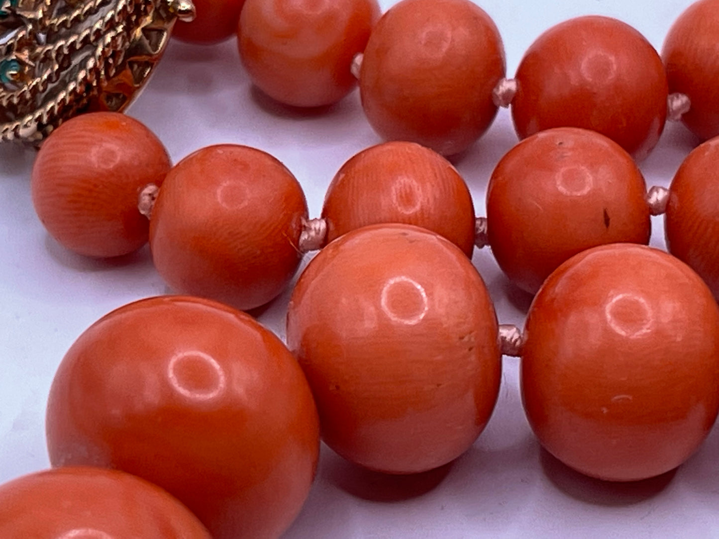 A vintage coral necklace with a 14k gold and emerald clasp