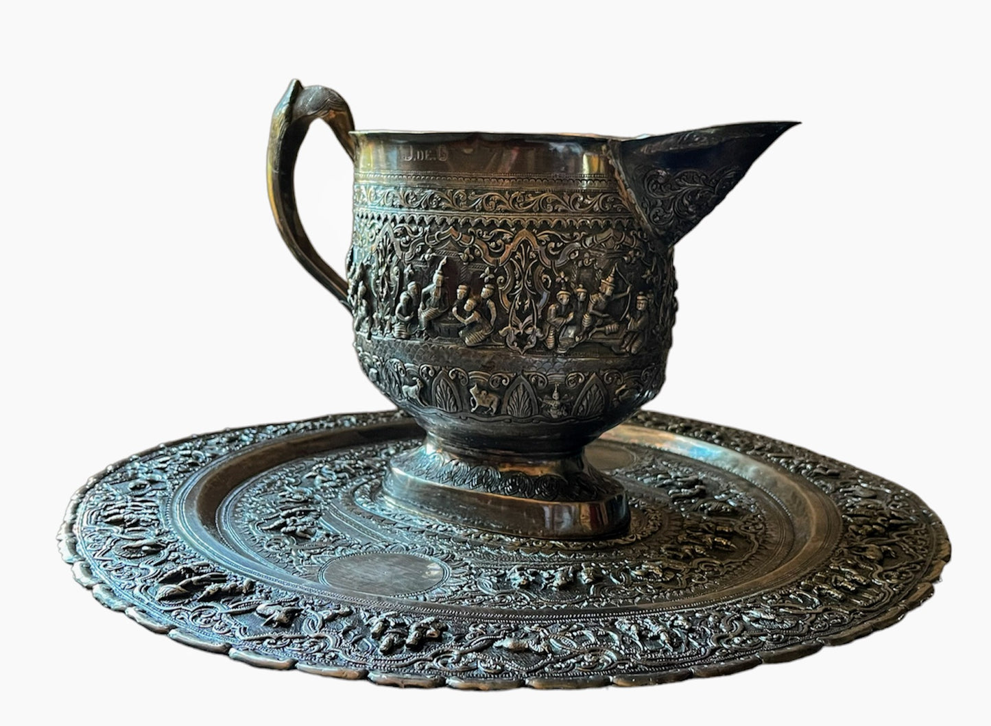 A Burmese antique elaborately carved circular tray and oval shaped jug with a pointed mug.