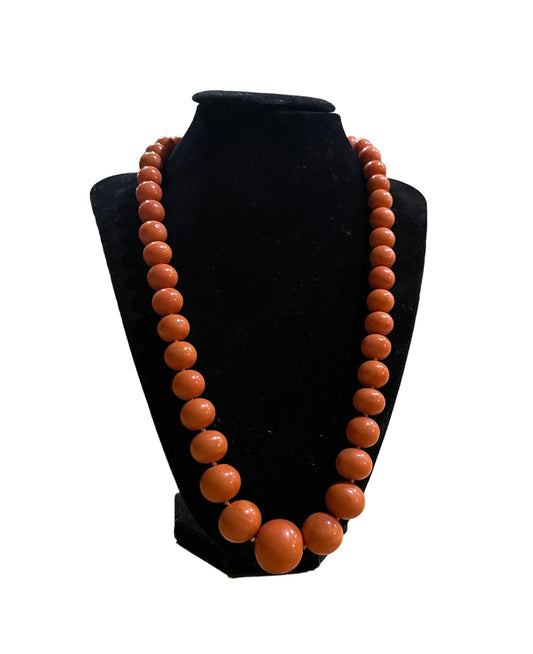 A vintage coral necklace with a 14k gold and emerald clasp