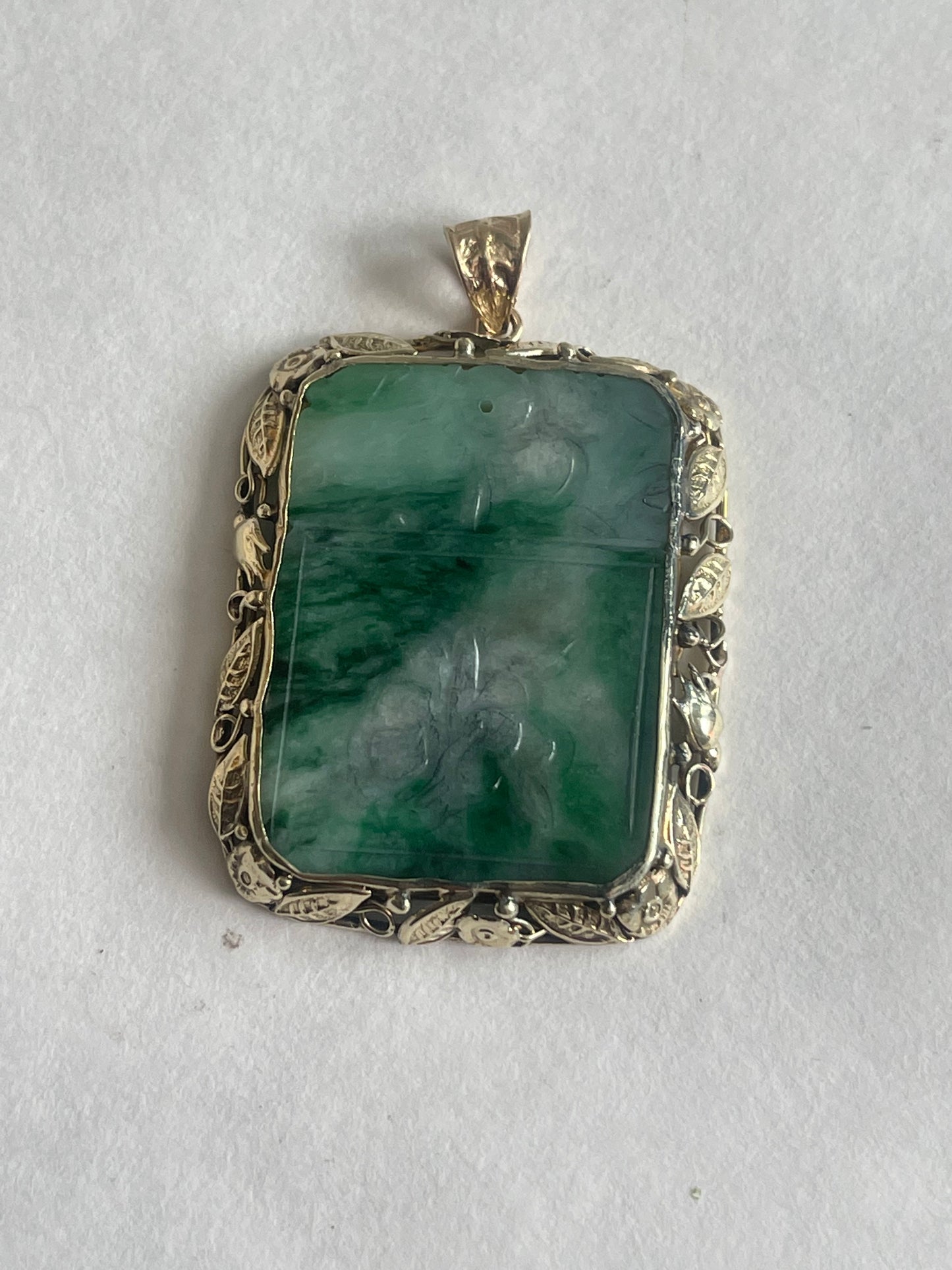 A vintage pendant with a jade plaque in a 10 kt setting