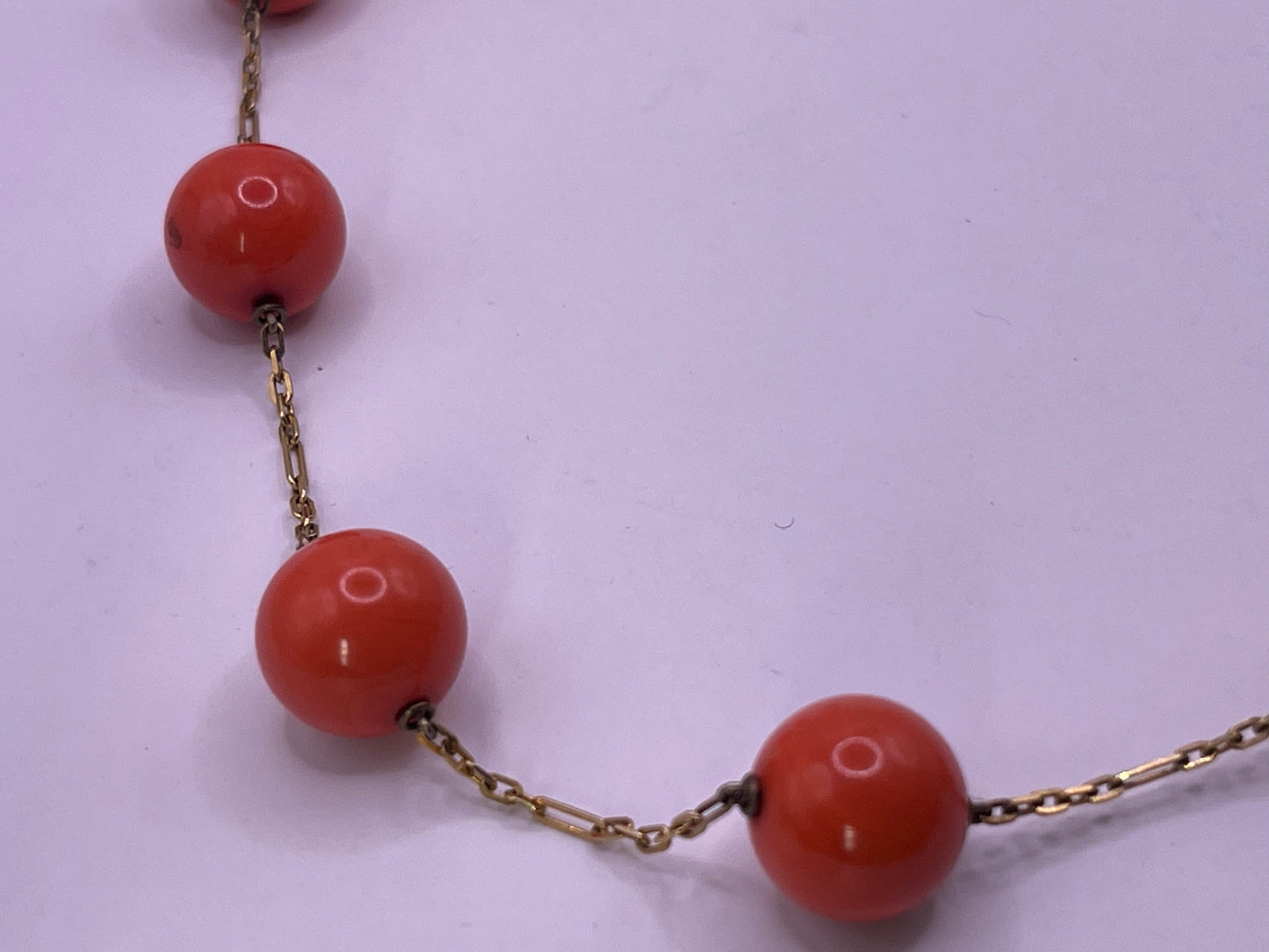 A necklace with coral beads on a 14kt chain