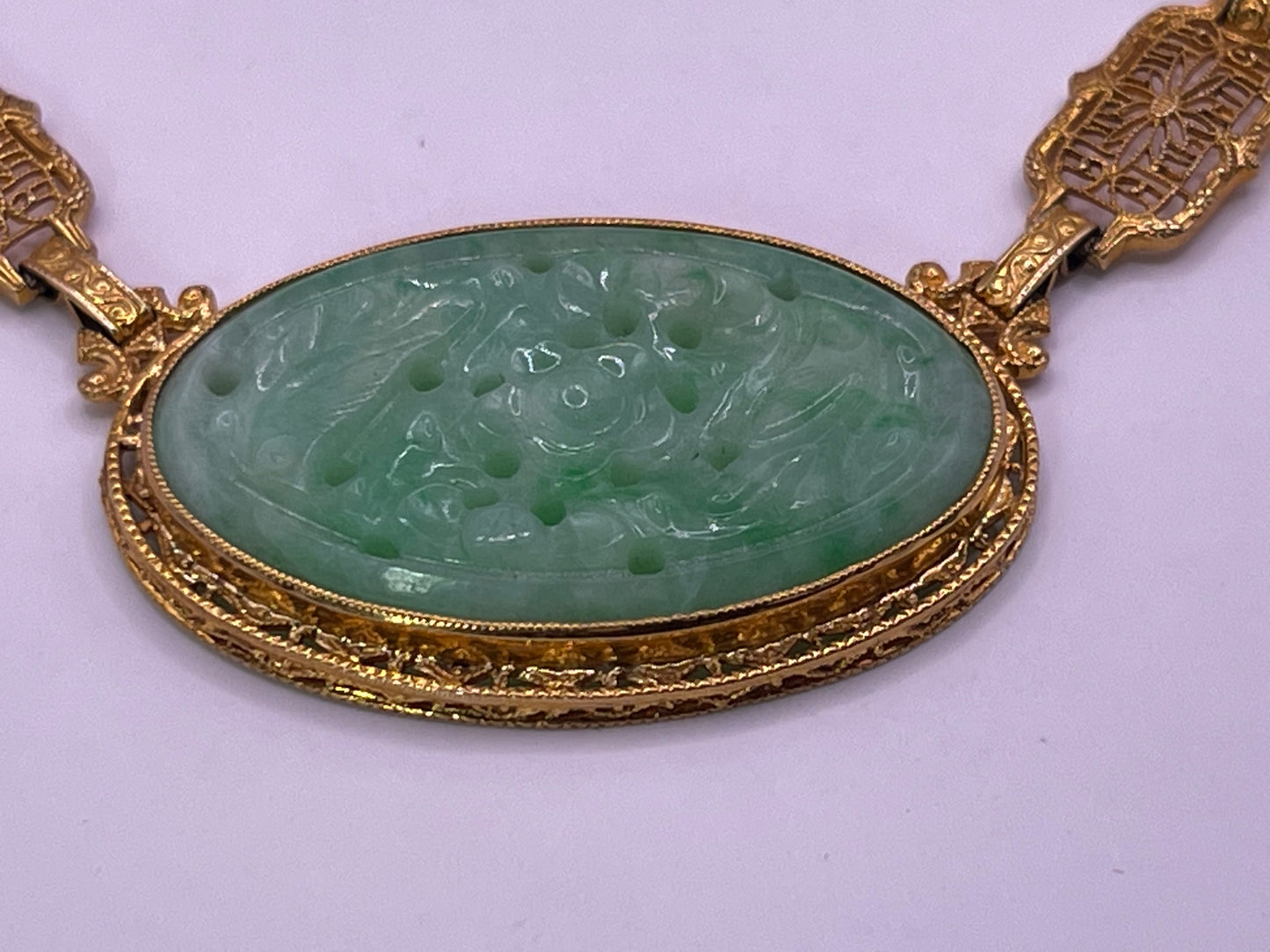 A vintage Art Deco style necklace with a antique apple green jade carved plaque in a 14kt filigree setting
