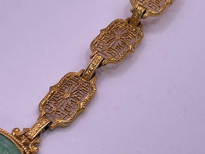 A vintage Art Deco style necklace with a antique apple green jade carved plaque in a 14kt filigree setting