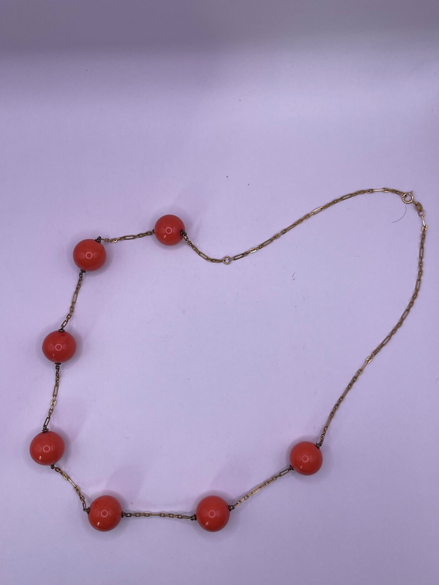A necklace with coral beads on a 14kt chain