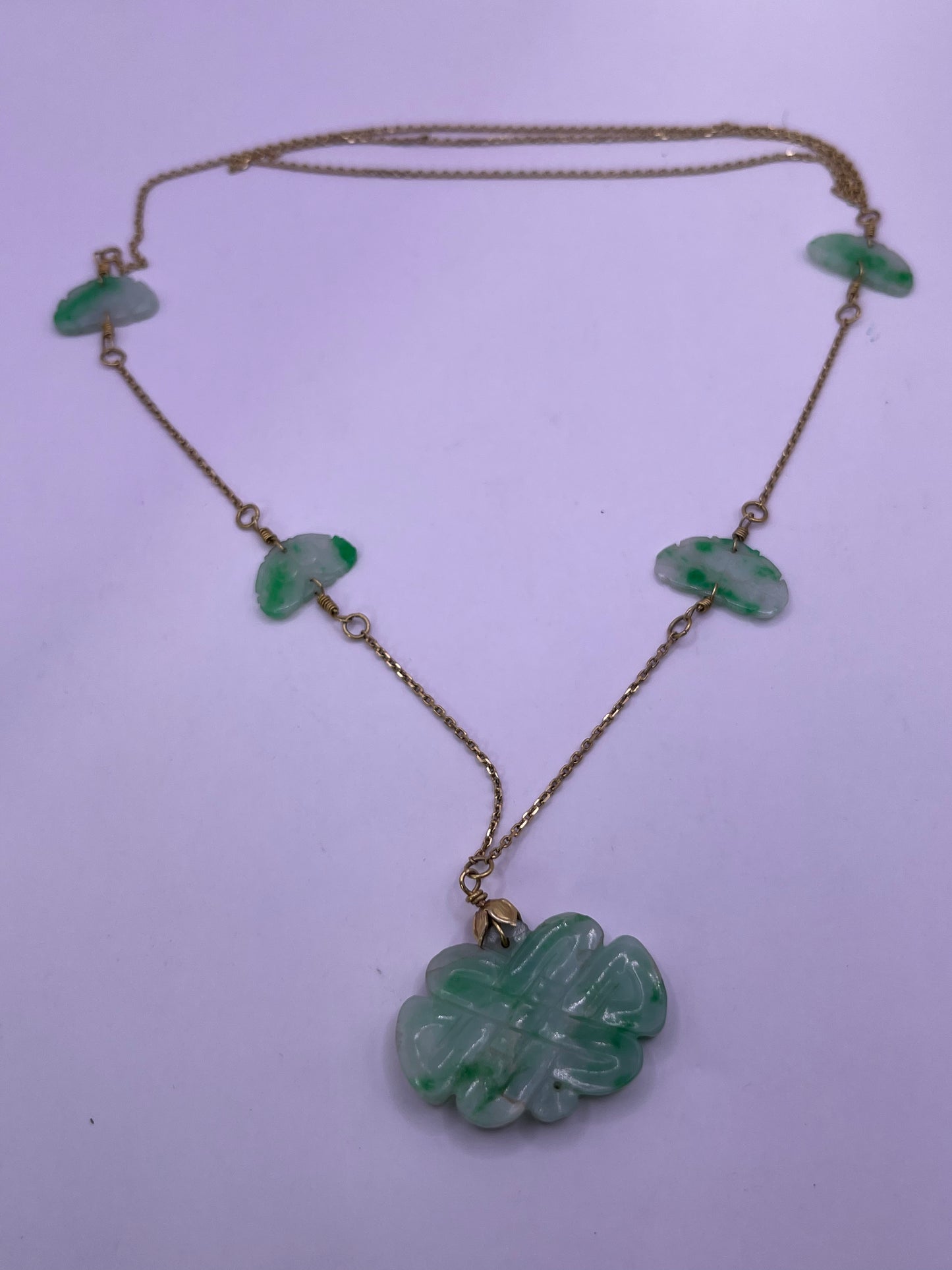A vintage Art Deco style necklace with an antique apple green jade carved plaque and smaller plaques on 14kt chain