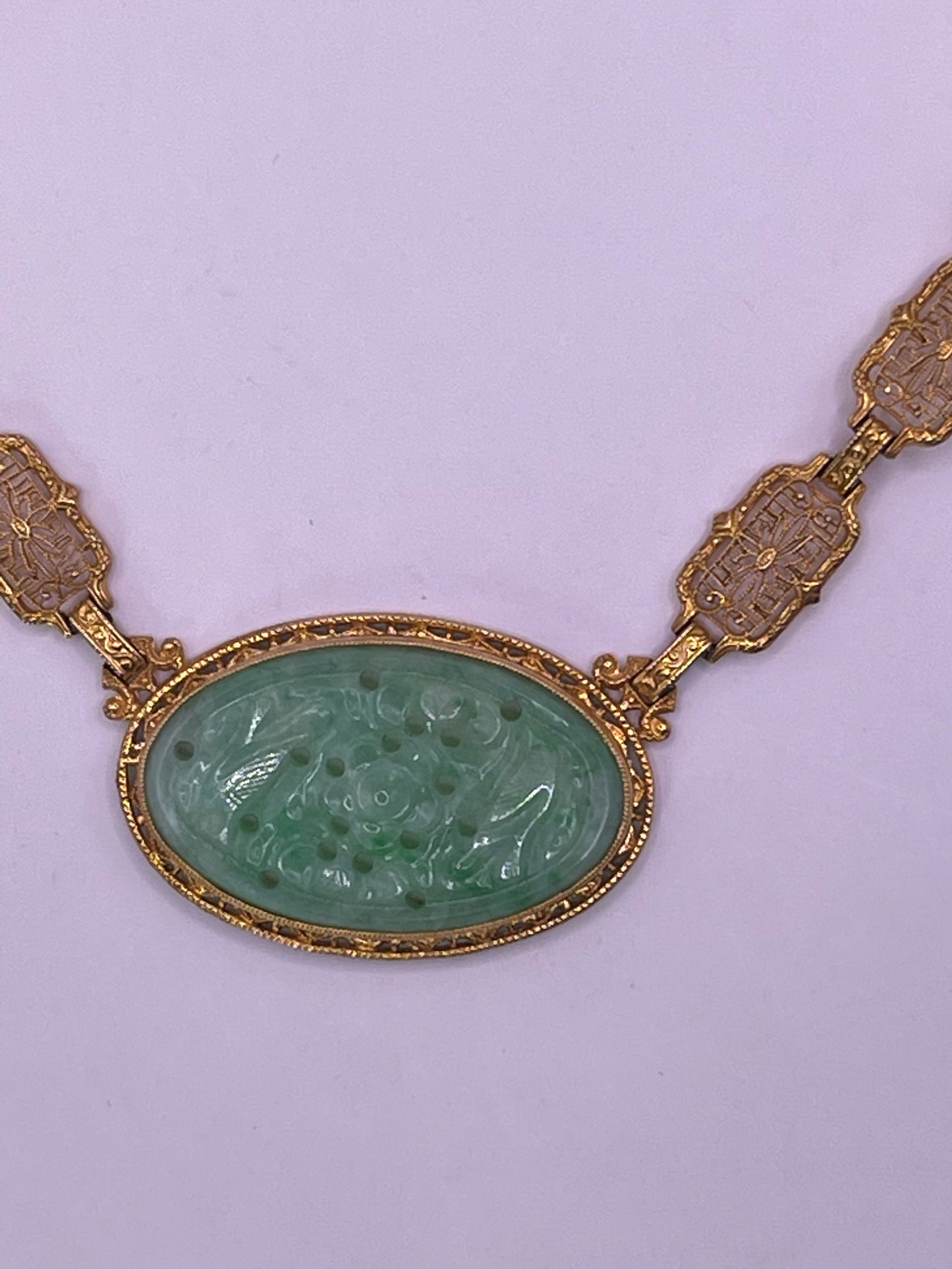 A vintage Art Deco style necklace with a antique apple green jade carved plaque in a 14kt filigree setting