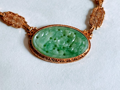 A vintage Art Deco style necklace with a antique apple green jade carved plaque in a 14kt filigree setting