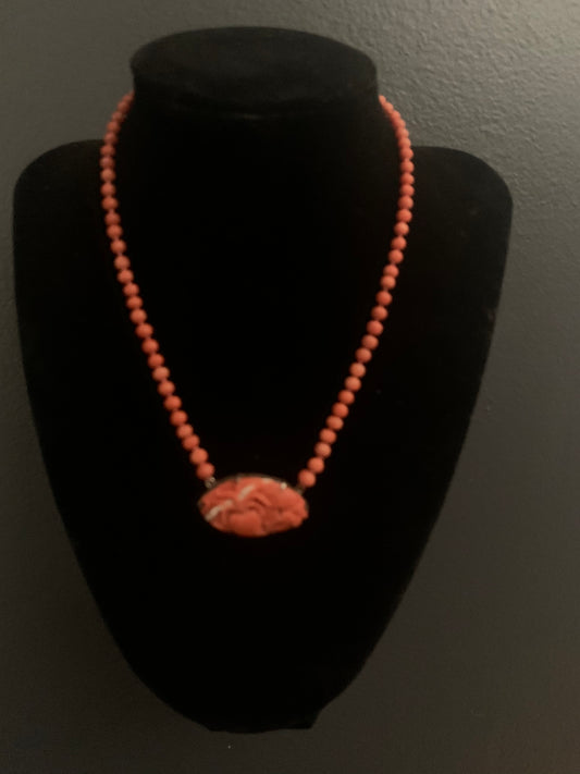 A coral necklace with a carved coral pendant
