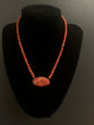A coral necklace with a carved coral pendant
