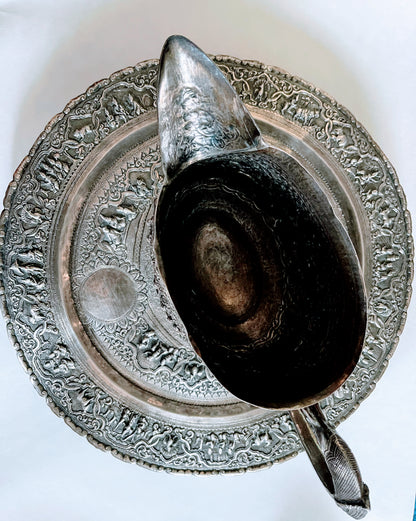 A Burmese antique elaborately carved circular tray and oval shaped jug with a pointed mug.