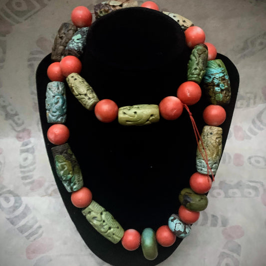 A necklace with antique carved turquoise and vintage coral beads