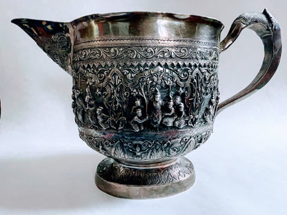 A Burmese antique elaborately carved circular tray and oval shaped jug with a pointed mug.