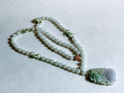A vintage Art Deco style necklace with a antique apple green jade carved plaque in a 14kt filigree setting