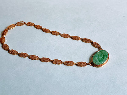 A vintage Art Deco style necklace with a antique apple green jade carved plaque in a 14kt filigree setting