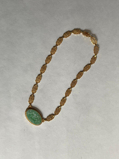 A vintage Art Deco style necklace with a antique apple green jade carved plaque in a 14kt filigree setting