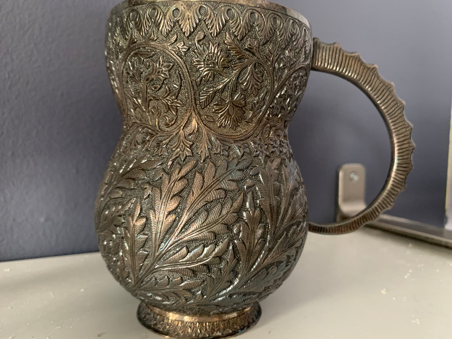 An intricately carved silver mug