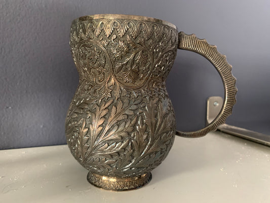 An intricately carved silver mug