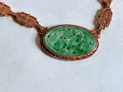 A vintage Art Deco style necklace with a antique apple green jade carved plaque in a 14kt filigree setting