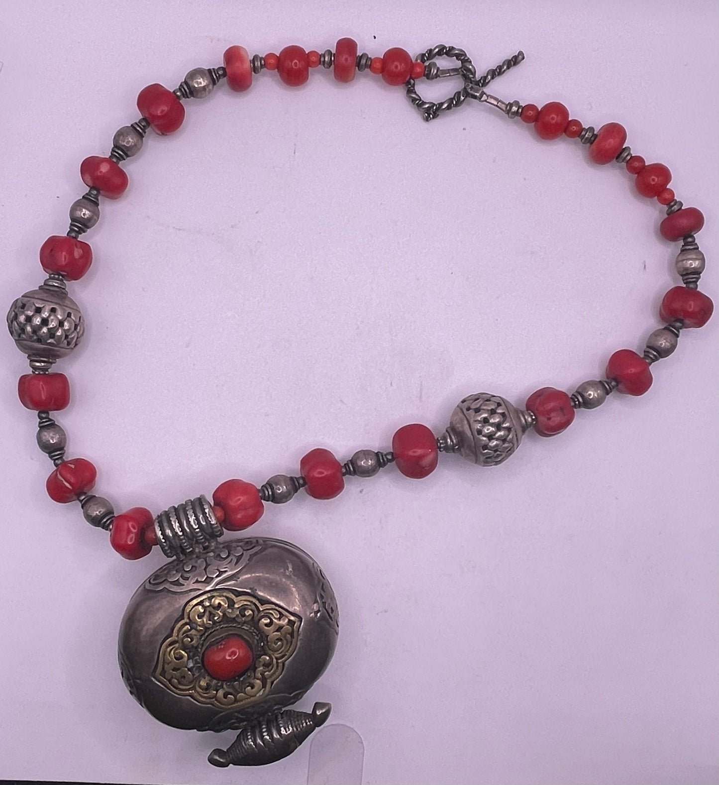 Antique Tibetan coral ghau pendant with a coral and silver necklace