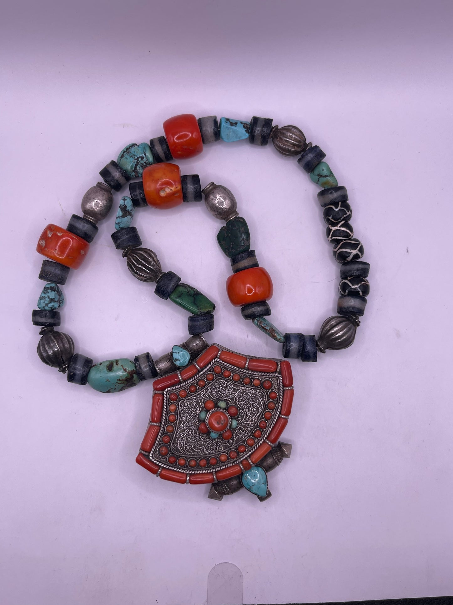A vintage Tibetan silver ghau with a necklace with assorted beads