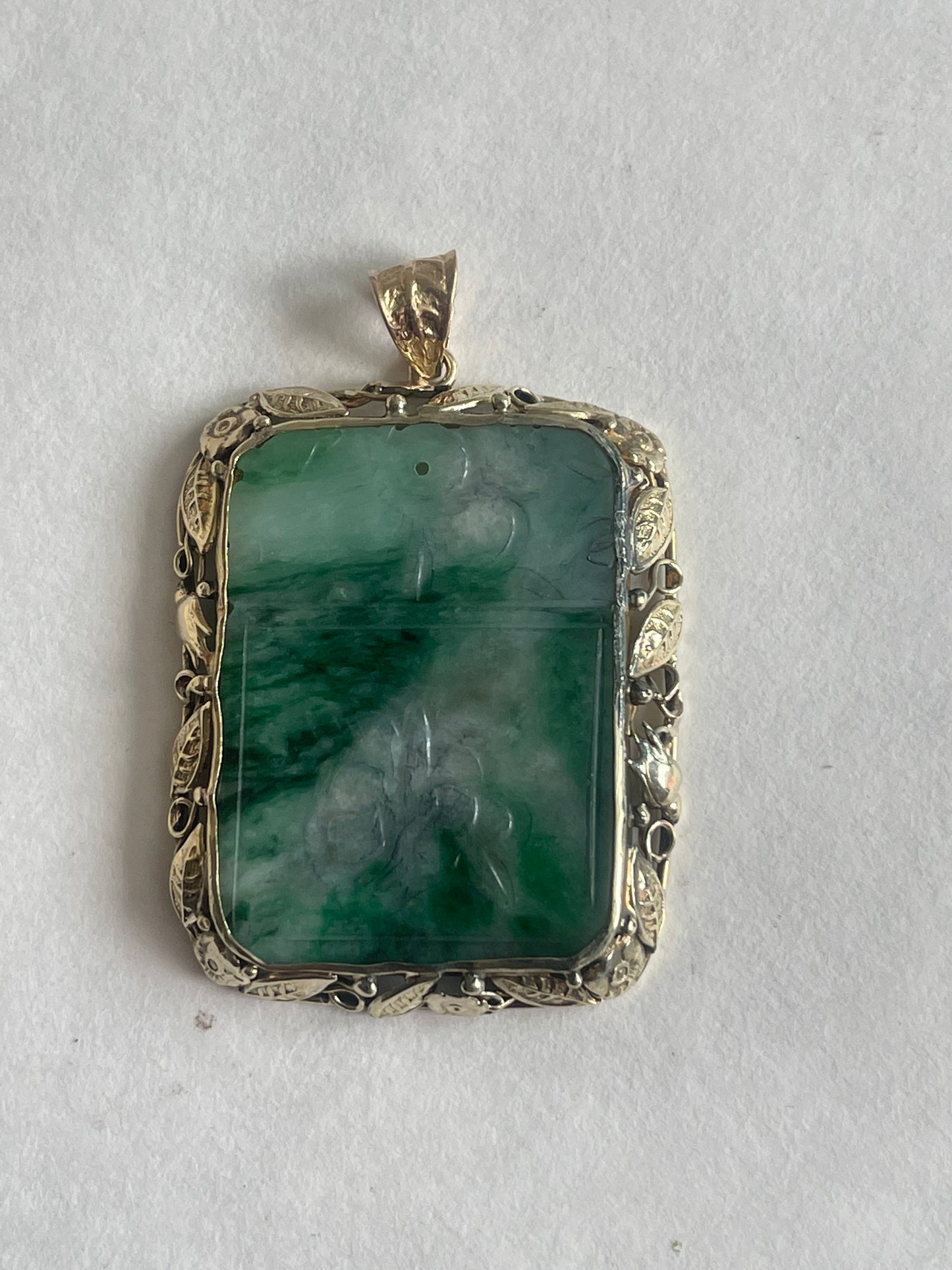 A vintage pendant with a jade plaque in a 10 kt setting