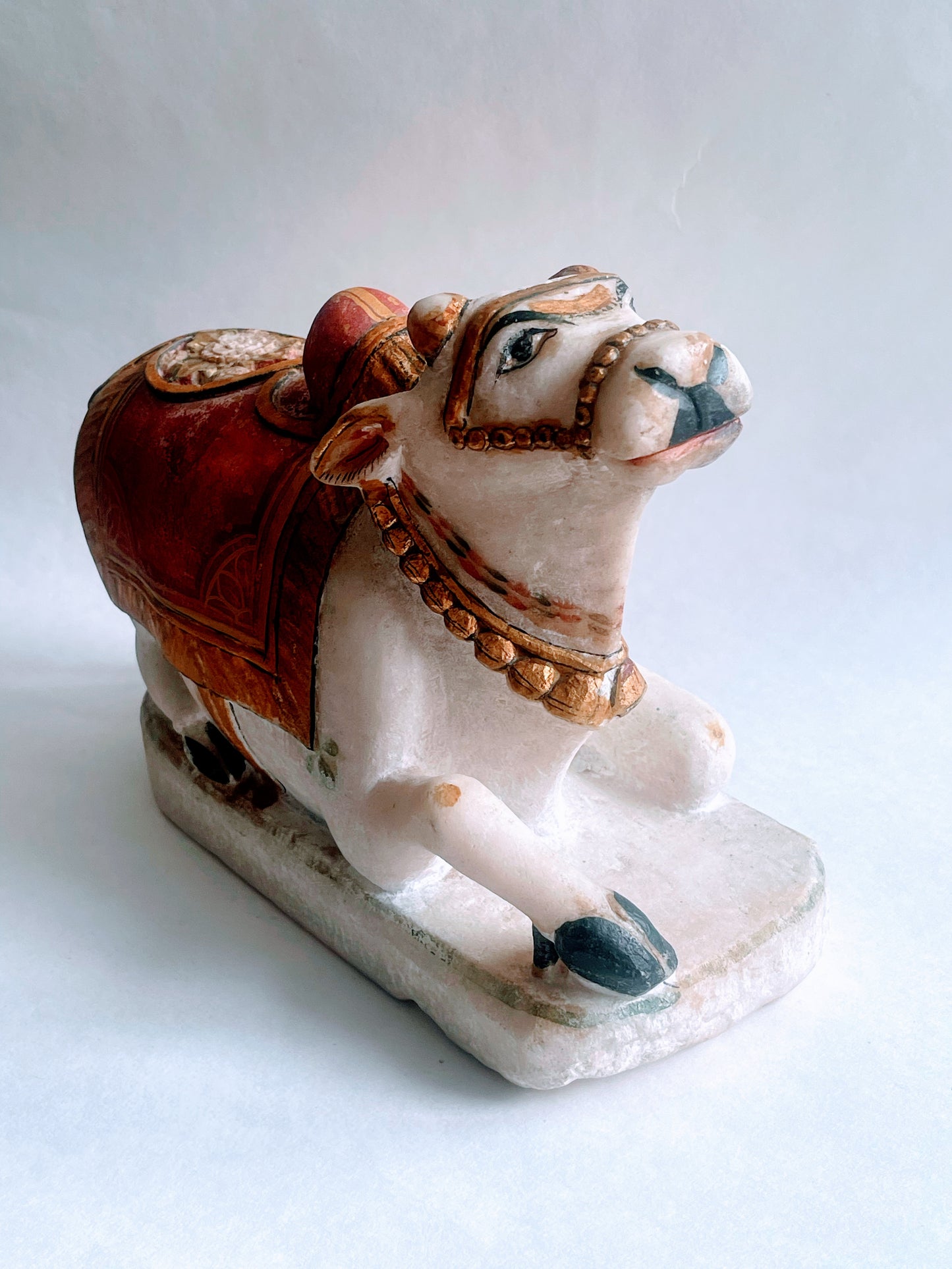 An antique polychromed carved marble statue of a bull- Nandi on