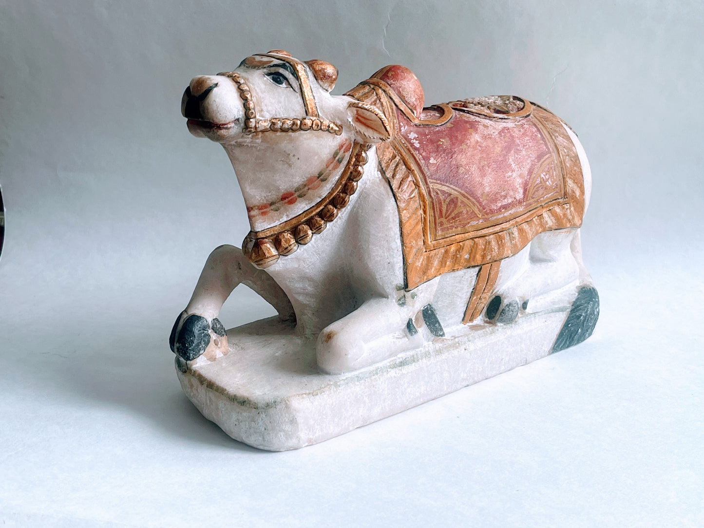 An antique polychromed carved marble statue of a bull- Nandi on