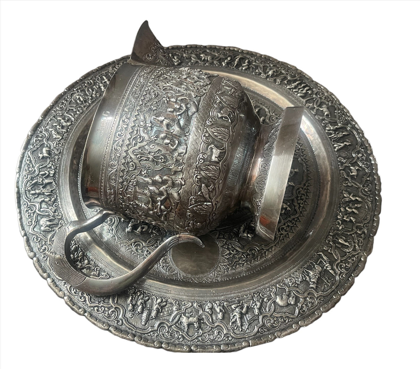 A Burmese antique elaborately carved circular tray and oval shaped jug with a pointed mug.
