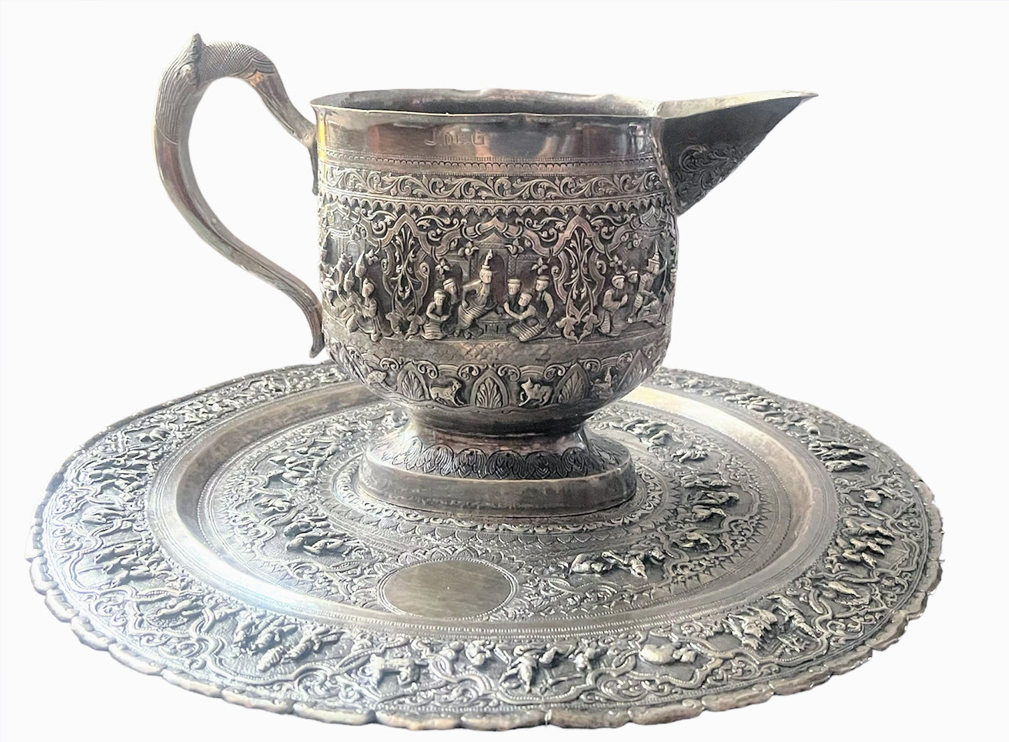 A Burmese antique elaborately carved circular tray and oval shaped jug with a pointed mug.