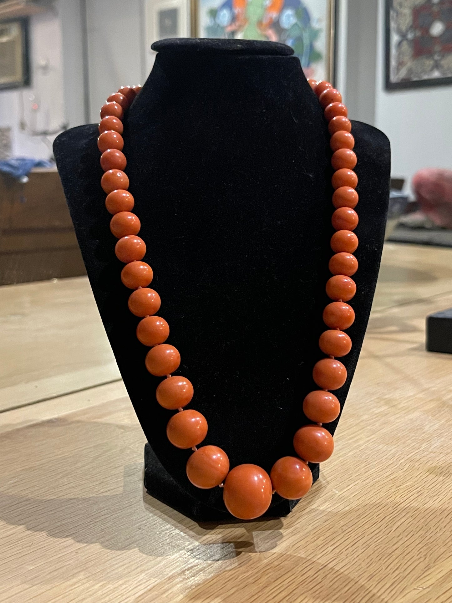 A vintage coral necklace with a 14k gold and emerald clasp