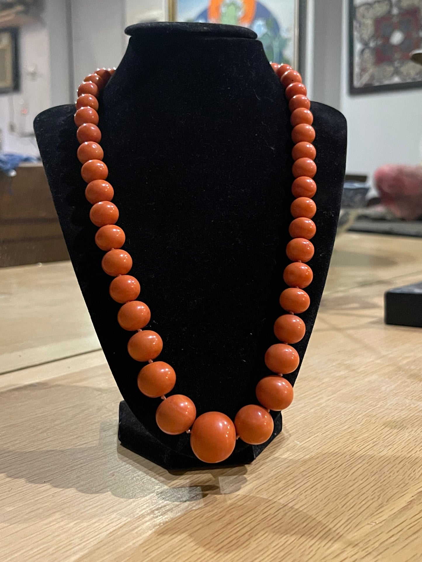 A vintage coral necklace with a 14k gold and emerald clasp