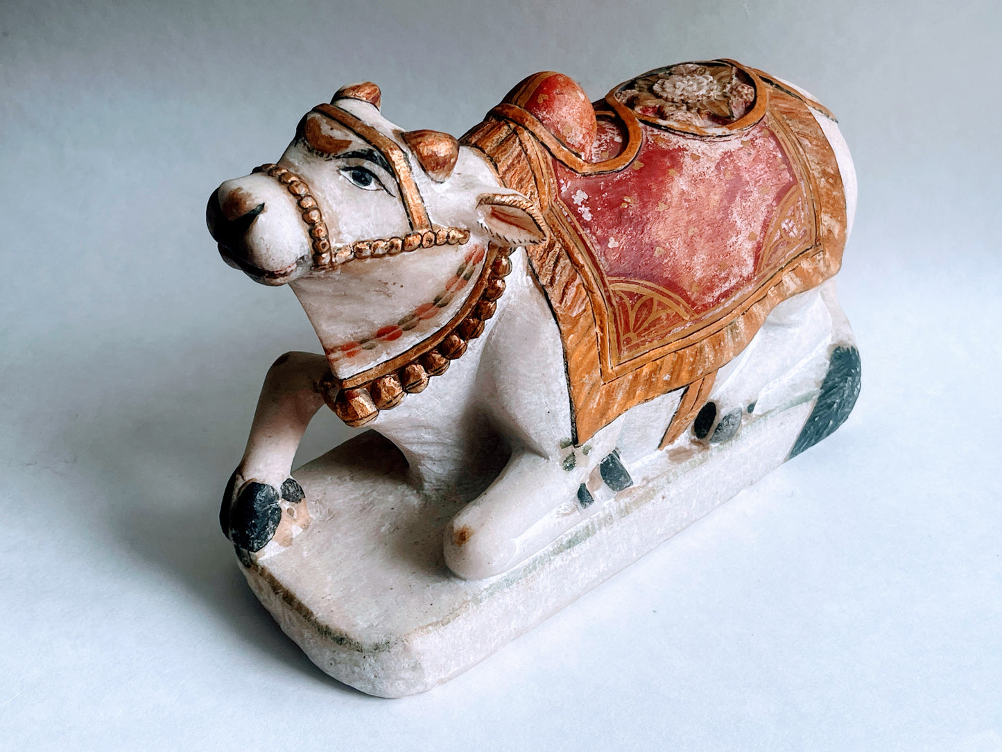 An antique polychromed carved marble statue of a bull- Nandi on