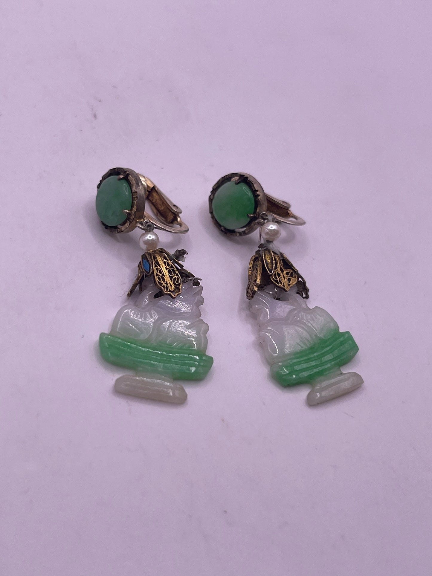 A pair of carved jade earrings in a gilded silver setting