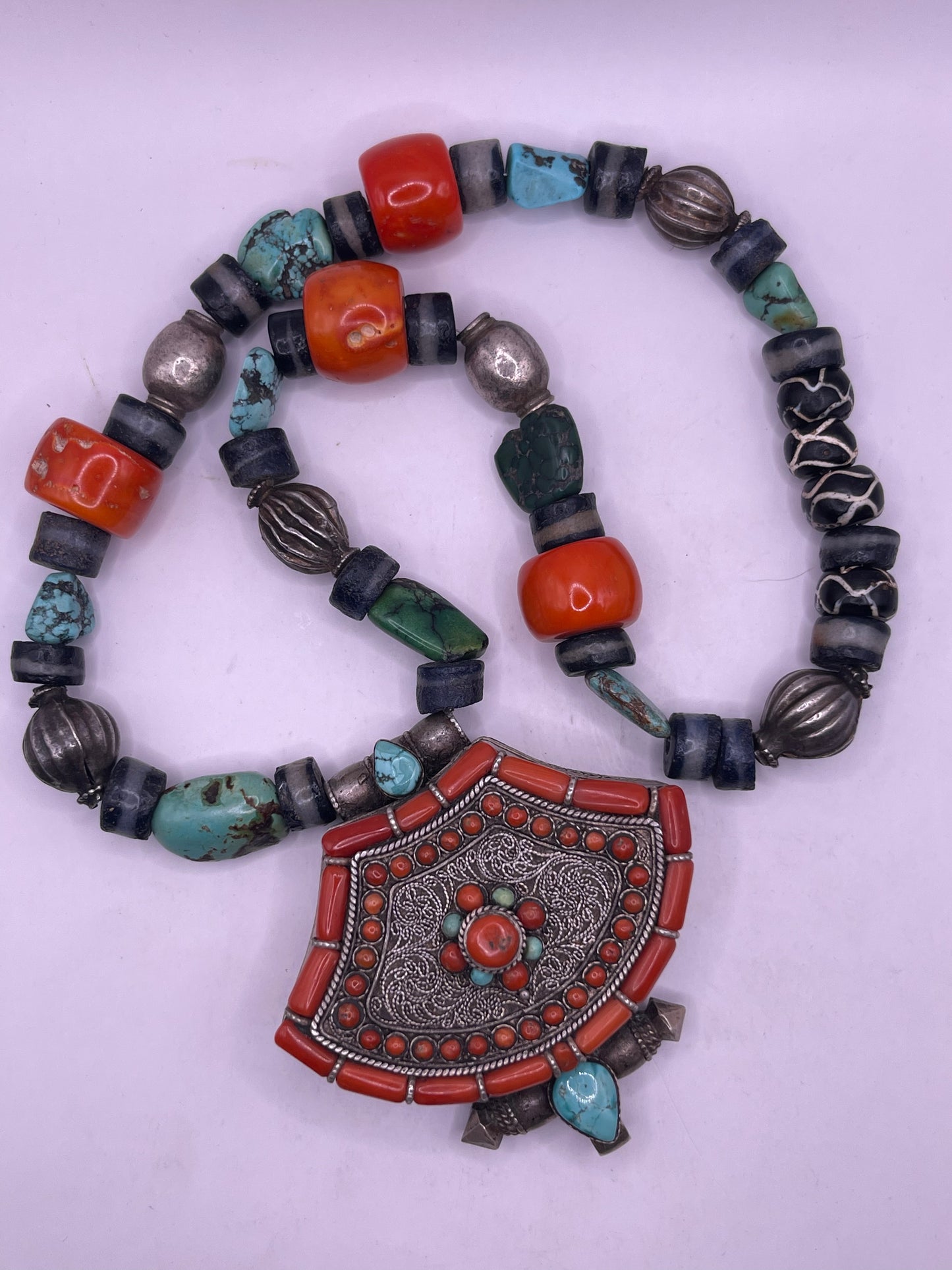 A vintage Tibetan silver ghau with a necklace with assorted beads