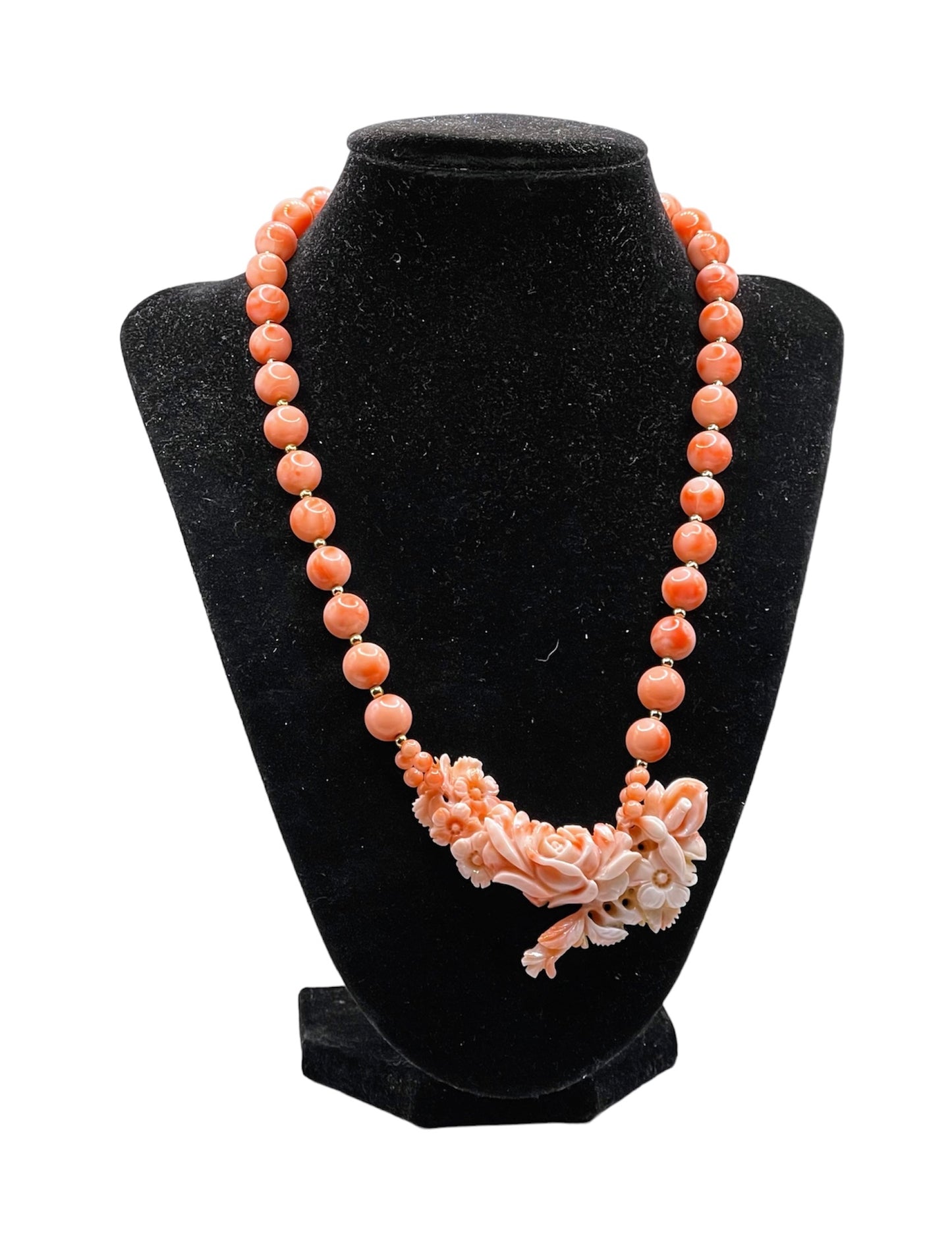 A coral necklace with coral beads and a carved coral pendant